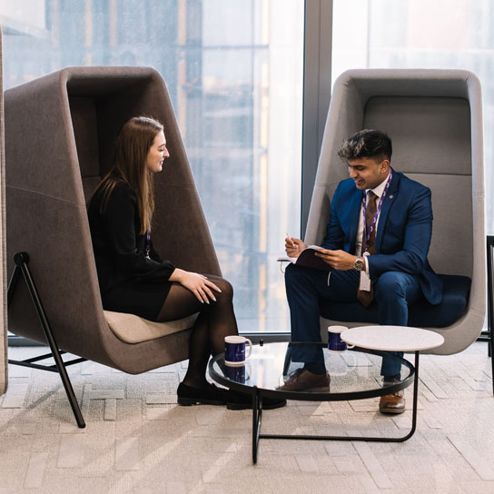 Man and woman sat in modern pod chairs in RSA London office