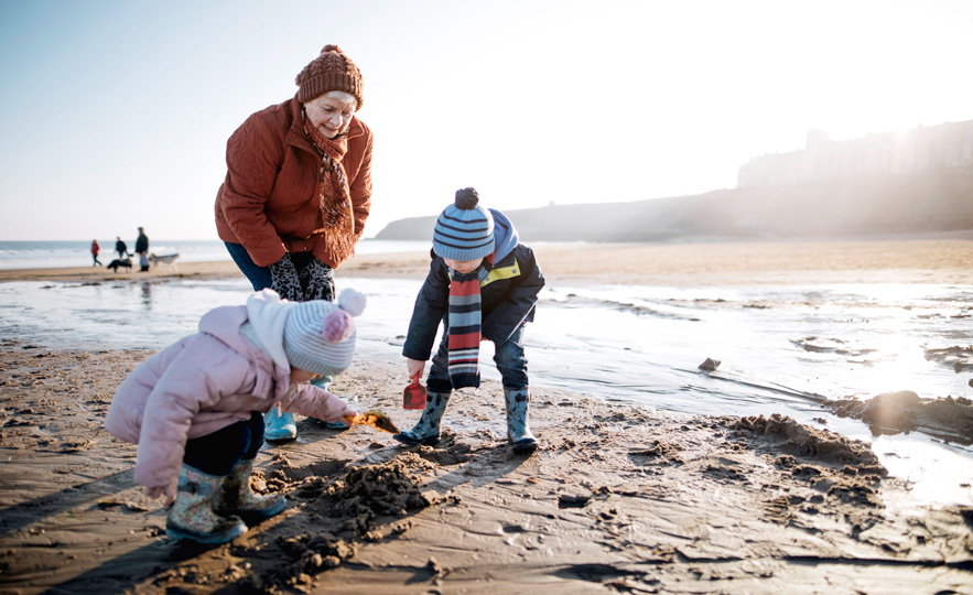 Older lady on the beach with 2 small children