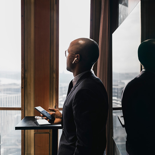 Man in office environment wearing suit using devices