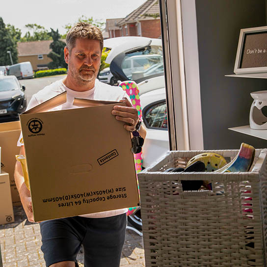 man carrying box into house