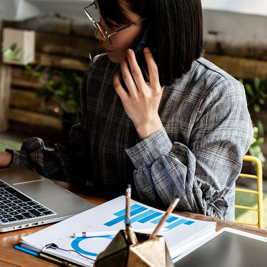 Woman on her phone looking at a laptop