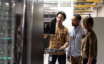 People looking at a computer screen with data servers