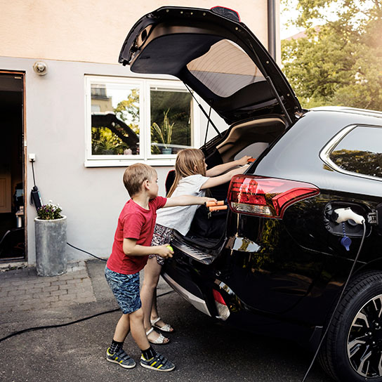 Children loading up boot of electric vehicle