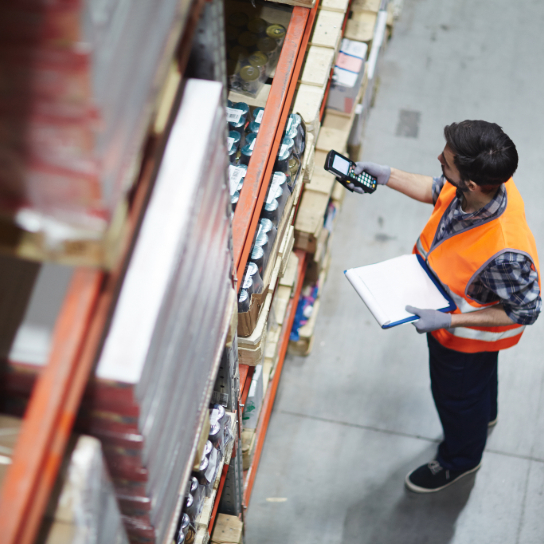 Man stood in warehouse scanning an item on shelving