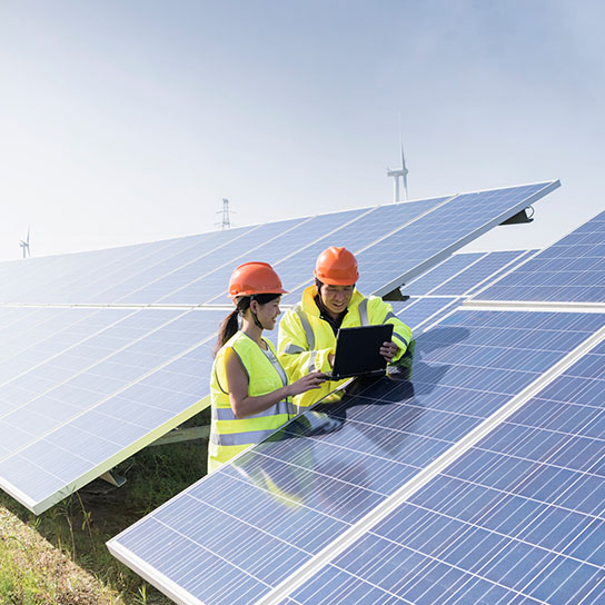Workers looking at a tablet next to solar panels