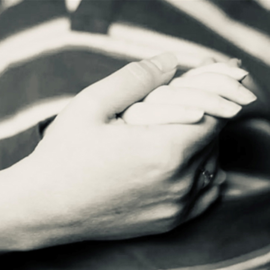 Black and white image of a parent holding a child's hand.