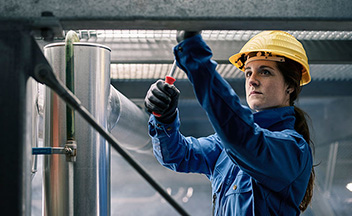 Woman using screwdriver wearing hard hat