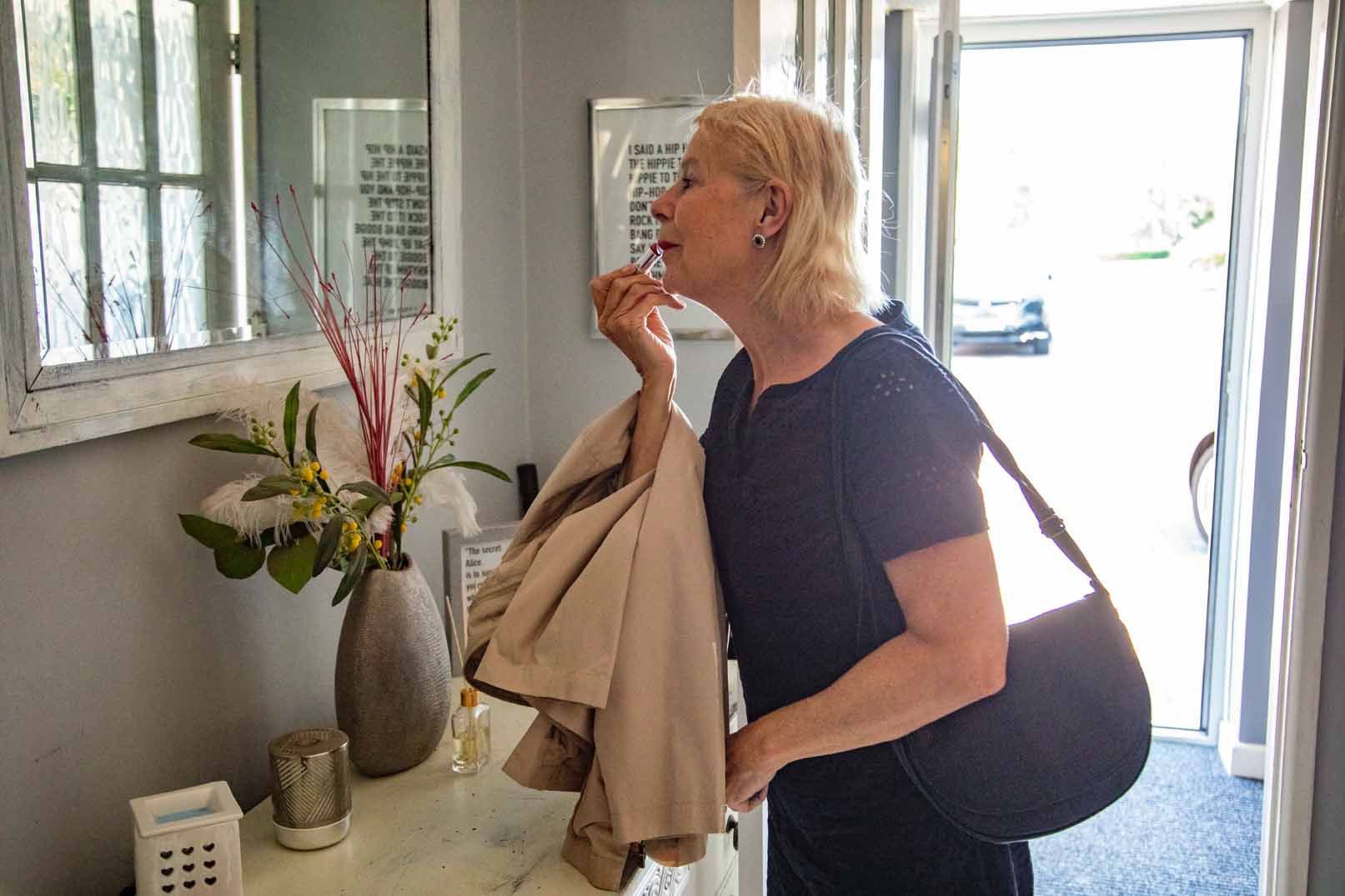 image of a woman applying lipstick in a mirror