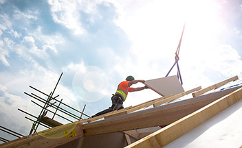 Worker on side of building installing wooden panels