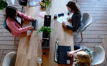 People working at a wooden desk in an office