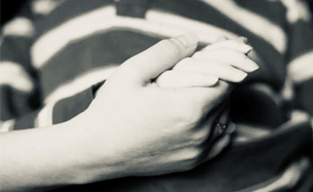 Black and white image of a parent holding a child's hand.