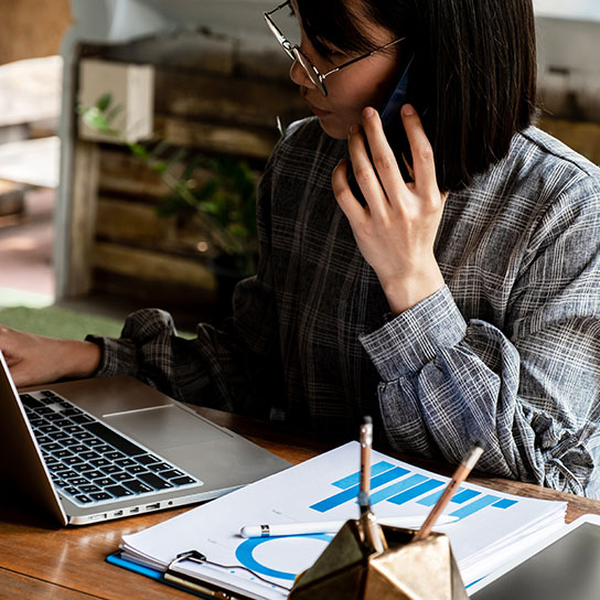 Woman on phone and laptop at desk