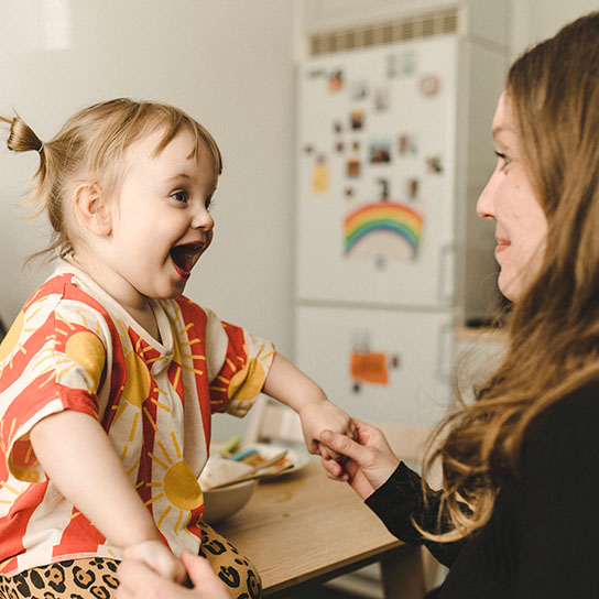 Young child sat on counter looking at parent