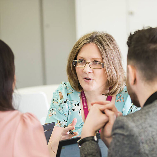 Woman wearing glasses talking to colleagues in an office