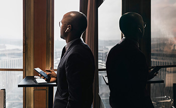Man in office environment wearing suit using devices