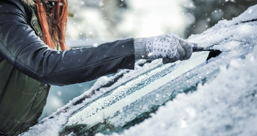 Woman scraping ice from a car windscreen