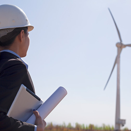 Woman in hard hat looking at wind turbine
