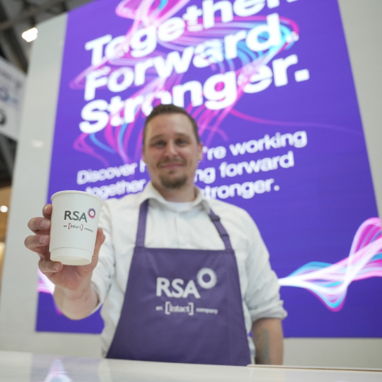 Photo from BIBA 2025 of a man holding an RSA and Intact branded coffee cup, in front of our stand display