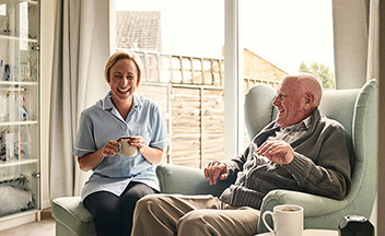 Carer with man laughing and drinking tea
